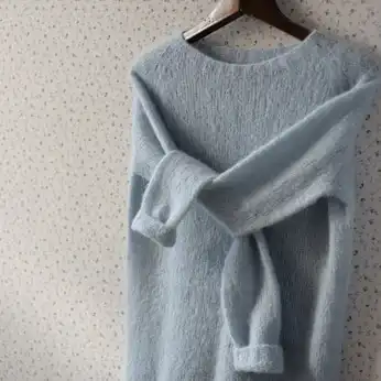 blue cashmere sweater on a wooden hanger with the arms crossed