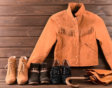 orange suede jacket with 3 pairs of suede boots and an umbrella