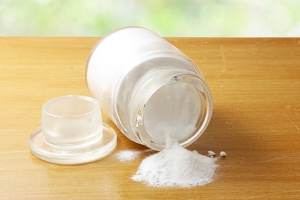 glass jar tipped over with baking soda coming out on a wooden table