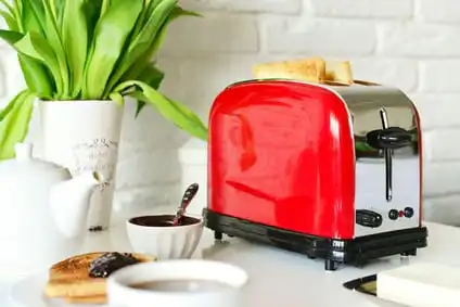 red toaster appliance in a white kitchen with a vase of flowers