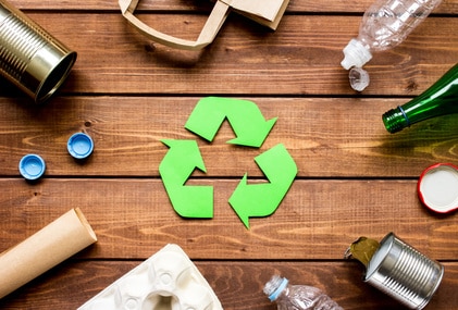 green recycle sign surrounded by recycled items