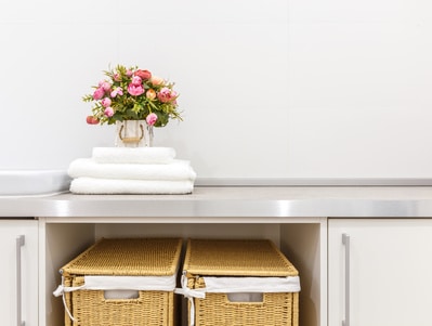 Organized laundry room with brown baskets and flowers on the counter