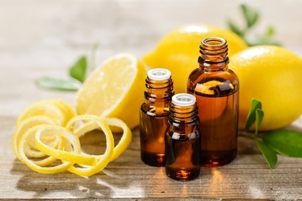 brown bottles of lemon essential oil with lemons and lemon rinds surrounding bottles